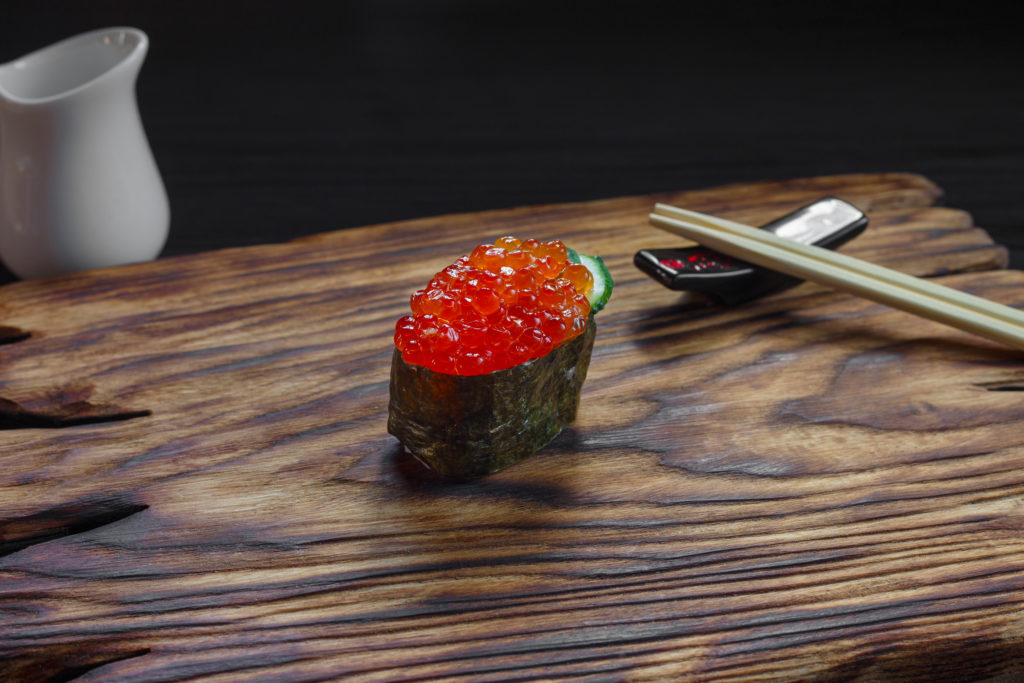 Delicious appetizing fresh one nigiri sushi with salmon caviar served on wooden rustic table,close-up. Japanese healthy seafood, traditional cuisine